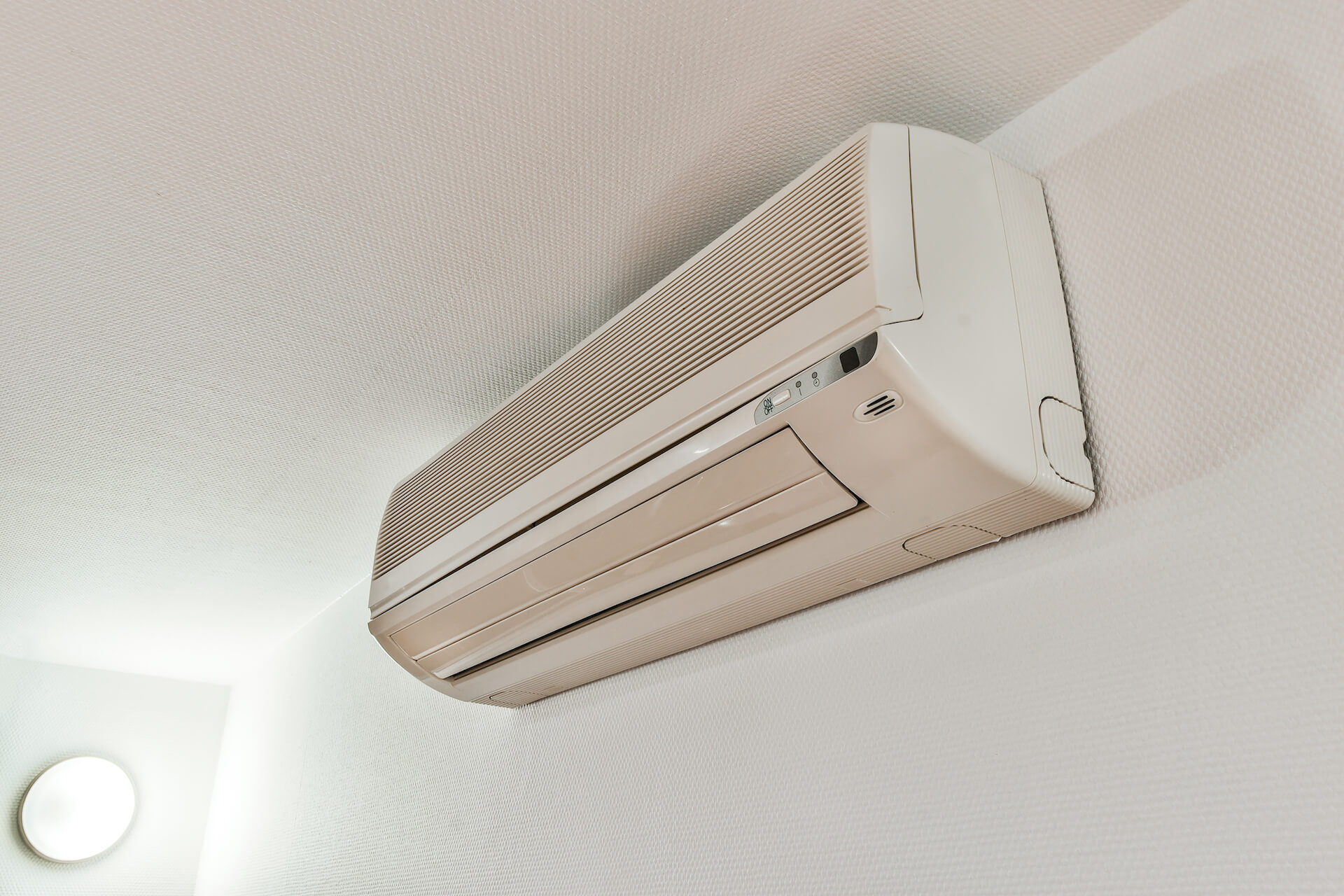 Photo of an air conditioner attached to a wall under a ceiling