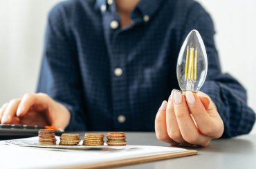 Photo of a person holding a light bulb and calculating money